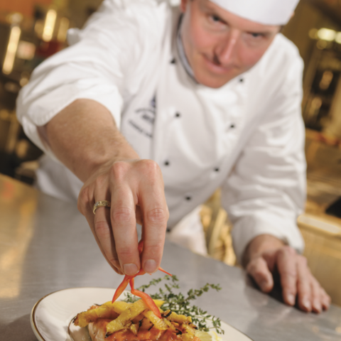 Chef placing a final touch to a meal about to be served.