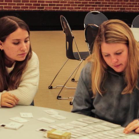 两个学生坐在桌子旁，看着桌子上的一个项目.