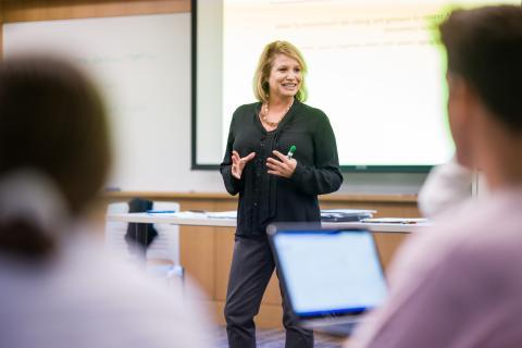 dynamic teacher presenting information in a classroom with a whiteboard in the background